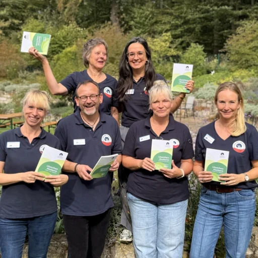 Sechs Mitarbeitende der Löwenherz-Akademie halten lachend das aktuelle Programmheft in den Händen