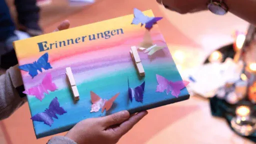 Ein Bild mit einem gemalten Sonnenuntergang, dem Wort Erinnerung und aufgeklebten Schmetterlingen aus Papier